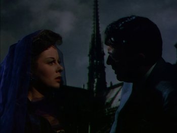 Movie still from “The Snows of Kilimanjaro” (1952), directed by Henry King – A man and a woman are standing next to each other in front of a building; Medium shot, Low angle