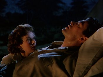 Movie still from “The Snows of Kilimanjaro” (1952), directed by Henry King – A man and a woman laying on the ground in the dark; Medium shot, Low angle
