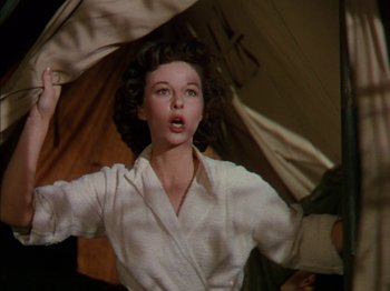 Movie still from “The Snows of Kilimanjaro” (1952), directed by Henry King – A woman in a white shirt is holding an umbrella; Medium shot, Low angle