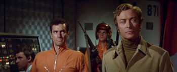 Movie still from “The Swarm” (1978), directed by Irwin Allen – A group of men standing next to each other in a room; Medium shot, Low angle