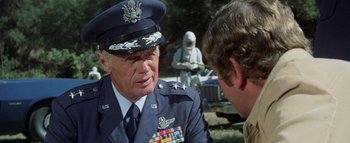 Movie still from “The Swarm” (1978), directed by Irwin Allen – An older man in a military uniform talking to another man; Close Up shot, Over the shoulder angle