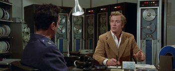 Movie still from “The Swarm” (1978), directed by Irwin Allen – Two men sitting at a table in front of each other; Medium shot, Over the shoulder angle