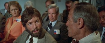 Movie still from “The Swarm” (1978), directed by Irwin Allen – A group of men in suits and ties sitting next to each other in a room; Close Up shot, Over the shoulder angle