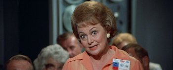 Movie still from “The Swarm” (1978), directed by Irwin Allen – An older woman in an orange shirt looking surprised; Close Up shot, Over the shoulder angle