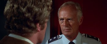 Movie still from “The Swarm” (1978), directed by Irwin Allen – An older man wearing a uniform looking at a younger man; Close Up shot, Over the shoulder angle