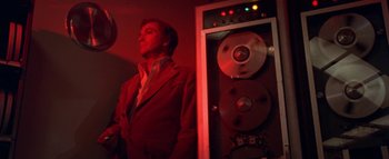 Movie still from “The Swarm” (1978), directed by Irwin Allen – A man standing in front of an audio system in a dark room; Medium shot, Low angle