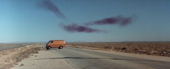 Movie still from “The Swarm” (1978), directed by Irwin Allen – An orange van driving down a road near a field; Extreme Wide shot, Low angle