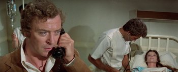 Movie still from “The Swarm” (1978), directed by Irwin Allen – A man talking on a phone next to another man; Close Up shot, Over the shoulder angle