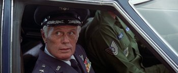 Movie still from “The Swarm” (1978), directed by Irwin Allen – An older man in a military uniform sitting in the back of a car; Close Up shot, Low angle