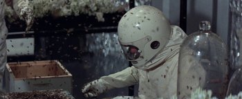 Movie still from “The Swarm” (1978), directed by Irwin Allen – A person in a spacesuit and a helmet is surrounded by bees; Medium shot, Overhead angle