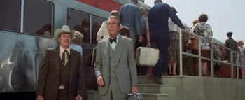Movie still from “The Swarm” (1978), directed by Irwin Allen – An older man in a suit and tie holding a briefcase; Medium shot, High angle