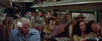 Movie still from “The Swarm” (1978), directed by Irwin Allen – A group of people sitting on a bus playing chess; Wide shot, High angle
