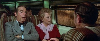 Movie still from “The Swarm” (1978), directed by Irwin Allen – An older woman sitting on a train looking out the window; Medium shot, High angle