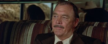 Movie still from “The Swarm” (1978), directed by Irwin Allen – An older man wearing a suit and tie; Close Up shot, Over the shoulder angle
