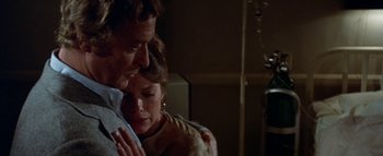 Movie still from “The Swarm” (1978), directed by Irwin Allen – A man and a woman embracing each other in a dark room; Close Up shot, Over the shoulder angle