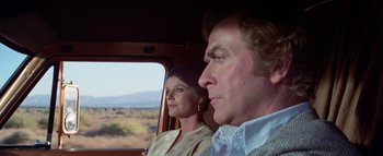 Movie still from “The Swarm” (1978), directed by Irwin Allen – A man and a woman sitting in a car looking out the window; Medium shot, Low angle