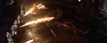 Movie still from “The Swarm” (1978), directed by Irwin Allen – A red car is on fire in a parking lot; Wide shot, High angle