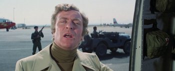 Movie still from “The Swarm” (1978), directed by Irwin Allen – An older man in a trench coat is looking at the camera; Close Up shot, Low angle
