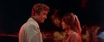 Movie still from “The Swarm” (1978), directed by Irwin Allen – A man and a woman standing next to each other in front of fire; Medium shot, Over the shoulder angle