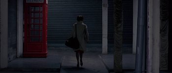 Movie still from “The Truth About Charlie” (2002), directed by Jonathan Demme – A woman walking down a street holding a bag; Wide shot, Over the shoulder angle