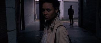 Movie still from “The Truth About Charlie” (2002), directed by Jonathan Demme – A woman standing in the street wearing a trench coat; Medium shot, High angle