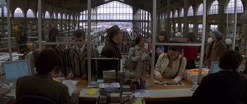 Movie still from “The Truth About Charlie” (2002), directed by Jonathan Demme – A group of people standing at a train station counter; Wide shot, High angle
