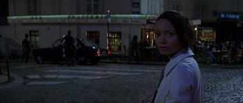 Movie still from “The Truth About Charlie” (2002), directed by Jonathan Demme – A woman standing on the side of the street at night; Medium shot, Over the shoulder angle