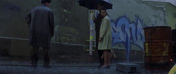 Movie still from “The Truth About Charlie” (2002), directed by Jonathan Demme – A woman standing under an umbrella in the pouring rain; Wide shot, Low angle
