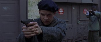 Movie still from “The Truth About Charlie” (2002), directed by Jonathan Demme – A man wearing a hat and holding a gun in his hand; Close Up shot, Low angle
