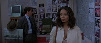 Movie still from “The Truth About Charlie” (2002), directed by Jonathan Demme – A woman standing in front of a wall with pictures on it; Medium shot, Over the shoulder angle