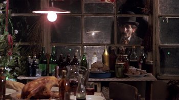 Movie still from “Time of the Gypsies” (1988), directed by Emir Kusturica – An old man sitting at a table in front of a bunch of bottles; Medium shot, Over the shoulder angle