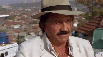 Movie still from “Time of the Gypsies” (1988), directed by Emir Kusturica – An older man wearing a hat and a white jacket; Close Up shot, Low angle