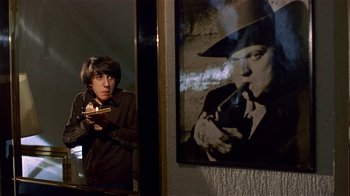 Movie still from “Time of the Gypsies” (1988), directed by Emir Kusturica – A young man looking in a mirror while holding a piece of pizza; Medium shot, Low angle