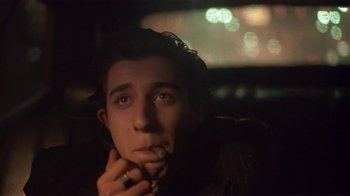 Movie still from “Time of the Gypsies” (1988), directed by Emir Kusturica – A man sitting in the back seat of a car with a cigarette in his mouth; Close Up shot, Low angle