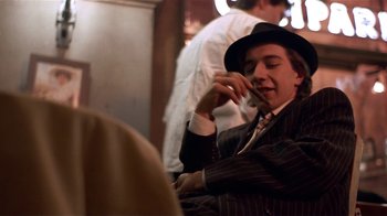Movie still from “Time of the Gypsies” (1988), directed by Emir Kusturica – A man in a suit and hat smoking a cigarette; Medium shot, Low angle