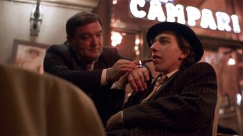 Movie still from “Time of the Gypsies” (1988), directed by Emir Kusturica – A man lighting a cigarette while another man looks on; Medium shot, Low angle
