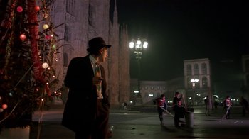 Movie still from “Time of the Gypsies” (1988), directed by Emir Kusturica – A man wearing a suit and a hat standing in front of a building; Wide shot, Low angle