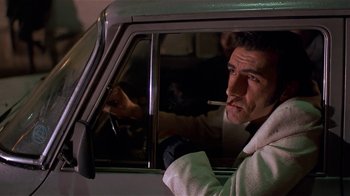 Movie still from “Time of the Gypsies” (1988), directed by Emir Kusturica – A man sitting in the drivers seat of a car while smoking a cigarette; Close Up shot, Low angle