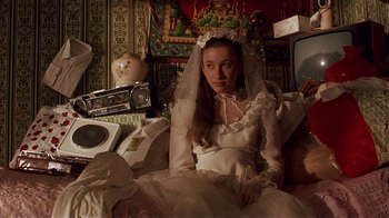 Movie still from “Time of the Gypsies” (1988), directed by Emir Kusturica – A woman in a wedding dress sitting on a couch; Medium shot, High angle