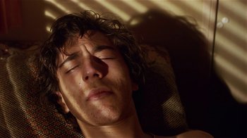 Movie still from “Time of the Gypsies” (1988), directed by Emir Kusturica – A young man is sleeping on a couch; Close Up shot, Overhead angle