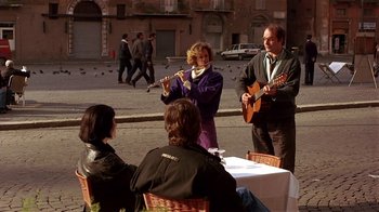 Movie still from “Time of the Gypsies” (1988), directed by Emir Kusturica – A group of people sitting at a table playing instruments; Wide shot, Over the shoulder angle