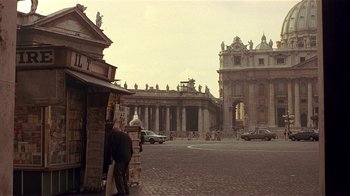Movie still from “Time of the Gypsies” (1988), directed by Emir Kusturica – A man standing in front of a building on a city street; Extreme Wide shot, Low angle