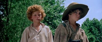 Movie still from “Tom Sawyer” (1973), directed by Don Taylor – Two people standing next to each other near a tree; Close Up shot, Low angle