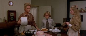 Movie still from “Tom Sawyer” (1973), directed by Don Taylor – A woman standing next to a boy in front of a cake; Medium shot, Over the shoulder angle