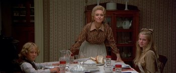 Movie still from “Tom Sawyer” (1973), directed by Don Taylor – An older woman sitting at a dinner table; Medium shot, Over the shoulder angle