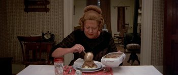 Movie still from “Tom Sawyer” (1973), directed by Don Taylor – An older woman cutting a cake on top of a table; Close Up shot, High angle