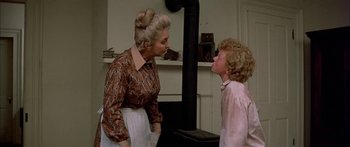 Movie still from “Tom Sawyer” (1973), directed by Don Taylor – An older woman and a young boy in front of a fireplace; Medium shot, Over the shoulder angle