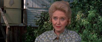 Movie still from “Tom Sawyer” (1973), directed by Don Taylor – An older woman with blue eyes and blonde hair wearing a floral shirt; Close Up shot, Over the shoulder angle