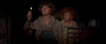 Movie still from “Tom Sawyer” (1973), directed by Don Taylor – A couple of people that are standing up in the dark; Medium shot, Low angle