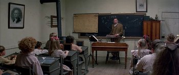 Movie still from “Tom Sawyer” (1973), directed by Don Taylor – A man is teaching a class in front of a chalkboard; Wide shot, High angle